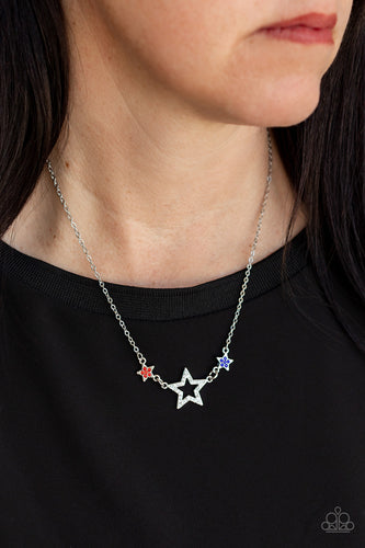 A white rhinestone encrusted silver star is flanked by two dainty blue and red rhinestone encrusted silver stars, creating a sparkly patriotic pendant below the collar. Features an adjustable clasp closure.  Sold as one individual necklace. Includes one pair of matching earrings.