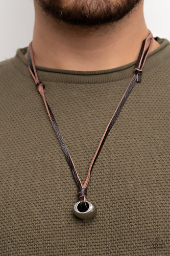 A chunky silver bead is knotted in place at the bottom of brown leather laces, resulting in an urban pendant. Features an adjustable sliding knot closure.  Sold as one individual necklace.