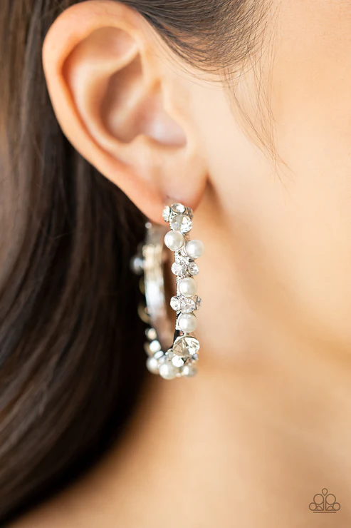 A bubbly array of classic white rhinestones and glassy white rhinestones are encrusted along the front of a silver hoop, creating an elegantly effervescent look. The earring attaches to a standard post-fitting. The hoop measures approximately 1 1/2