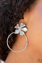 Load image into Gallery viewer, Featuring lifelike textures, a shimmery silver buttercup blooms atop an oversized silver hoop for a whimsical allure. The earring attaches to a standard post-fitting.  Sold as one pair of post earrings.
