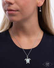 Load image into Gallery viewer, Swimming along a dainty silver chain, an oversized silver turtle pendant with a Grass Green pearl-painted and white rhinestone embellished shell and eyes shimmers below the neckline for a classic, coastal look. Features an adjustable clasp closure.
