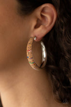 Load image into Gallery viewer, A cork lined silver hoop is splattered in multicolored paint, creating a colorful display. Hoop measures approximately 2&quot; in diameter. Earring attaches to a standard post fitting.  Sold as one pair of hoop earrings.
