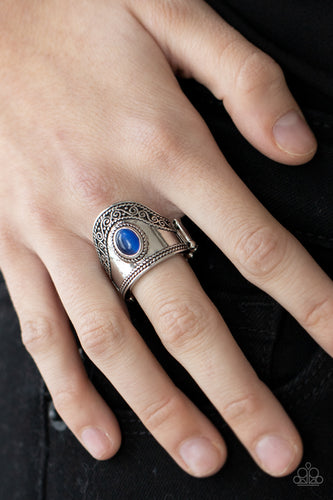 An oval blue cat's eye stone adorns the center of a rounded silver frame trimmed in ropelike and vine-like filigree, creating a whimsical centerpiece atop the finger. Features a stretchy band for a flexible fit.  Sold as one individual ring.