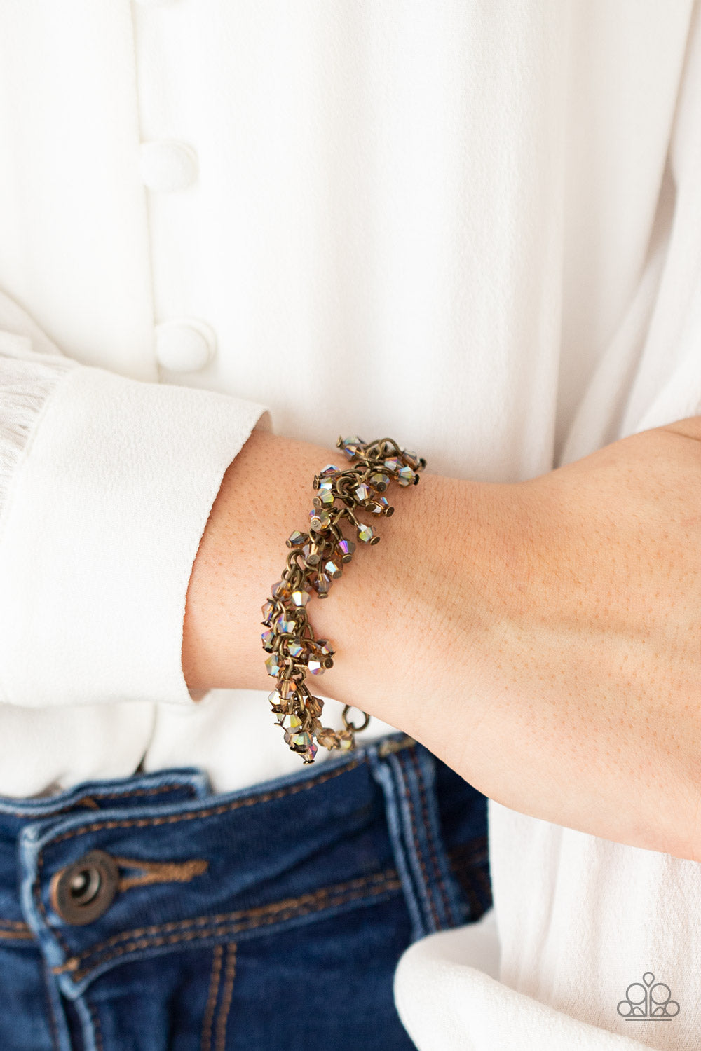 Dainty brassy tone-on-tone iridescent beads swing from a classic brass chain, creating a clustered fringe around the wrist. Features an adjustable clasp closure.  Sold as one individual bracelet.