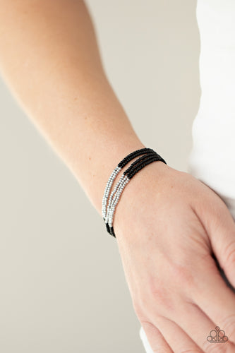 Four strands of black micro beads are accented with a bold section of silver beads for a simple yet trendy look. Features an adjustable sliding knot closure.  Sold as one individual bracelet.