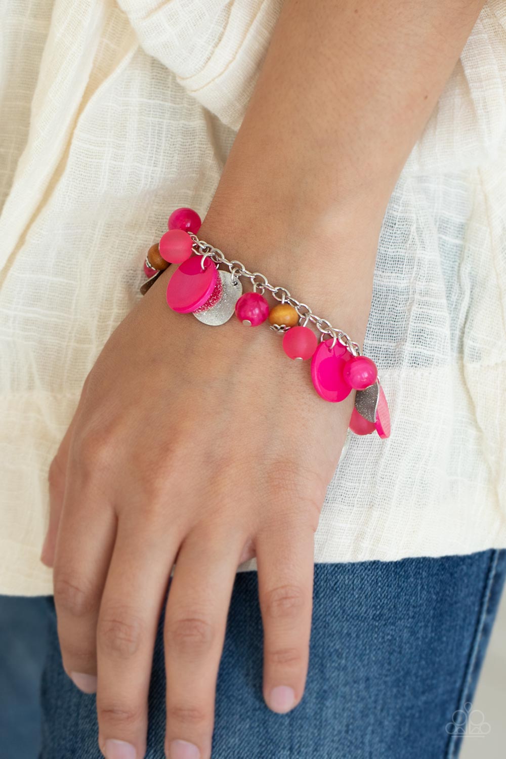 Infused with wooden beads and silver discs, an earthy collection of glassy, opaque, and shell-like Raspberry Sorbet beads swing from the wrist, creating a springtime inspired fringe. Features an adjustable clasp closure.