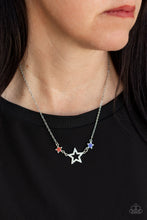 Load image into Gallery viewer, A white rhinestone encrusted silver star is flanked by two dainty blue and red rhinestone encrusted silver stars, creating a sparkly patriotic pendant below the collar. Features an adjustable clasp closure.  Sold as one individual necklace. Includes one pair of matching earrings.
