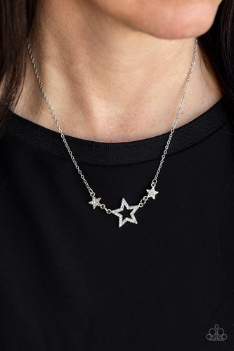 A white rhinestone encrusted silver star is flanked by two dainty white rhinestone encrusted silver stars, creating a sparkly patriotic pendant below the collar. Features an adjustable clasp closure.  Sold as one individual necklace. Includes one pair of matching earrings.