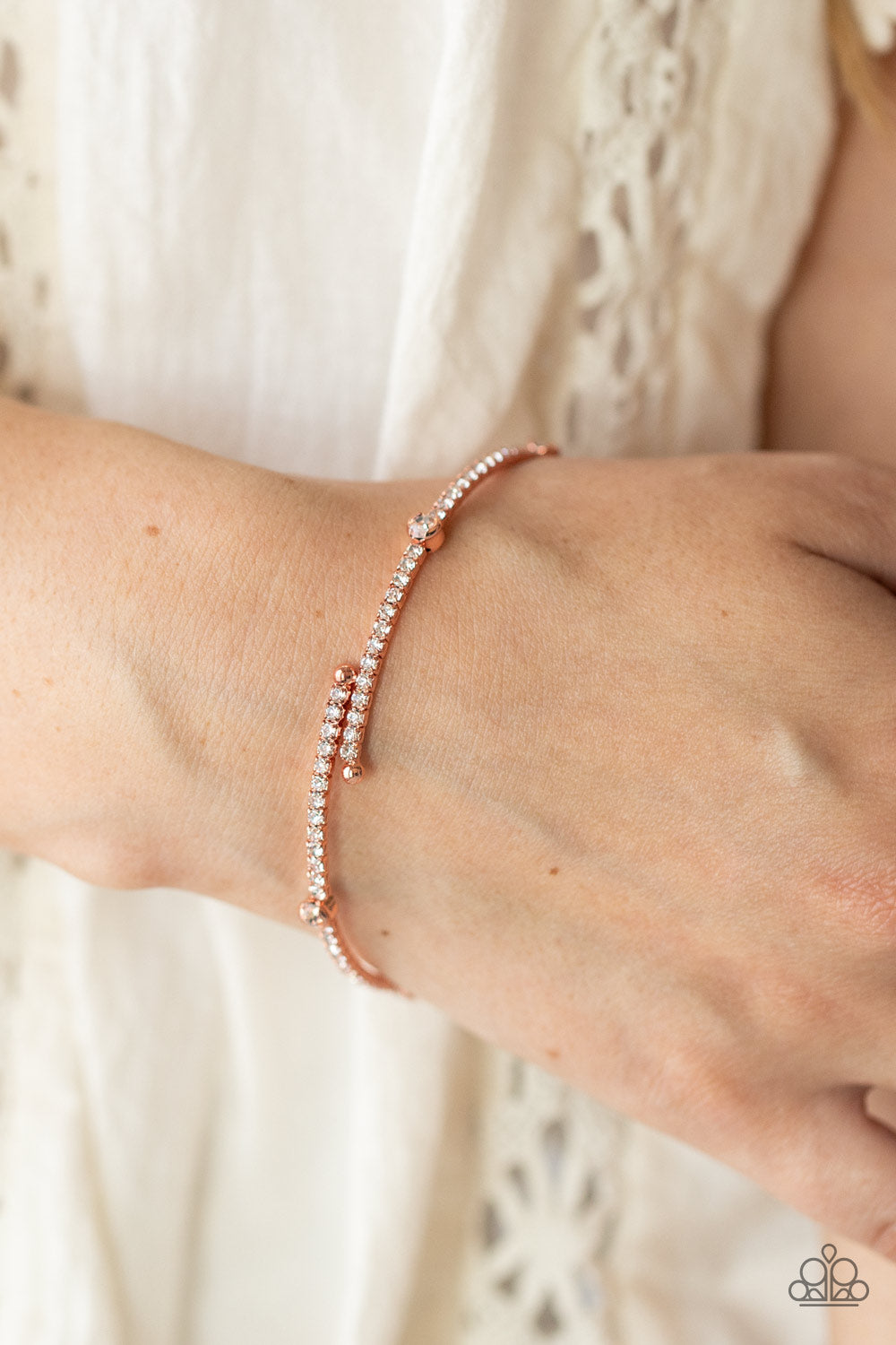 Encased in shiny copper fittings, a sparkly collection of solitaire white rhinestones adorn a glittery strand of dainty white rhinestones that coil around the wrist, creating a dainty cuff.  Sold as one bracelet.