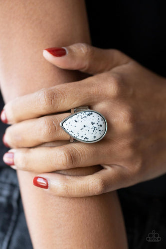 A generous polished white stone infused with black flecks is encased in a simple silver teardrop frame resulting in a seasonal finish atop the finger. Features a stretchy band for a flexible fit.  Sold as one individual ring.