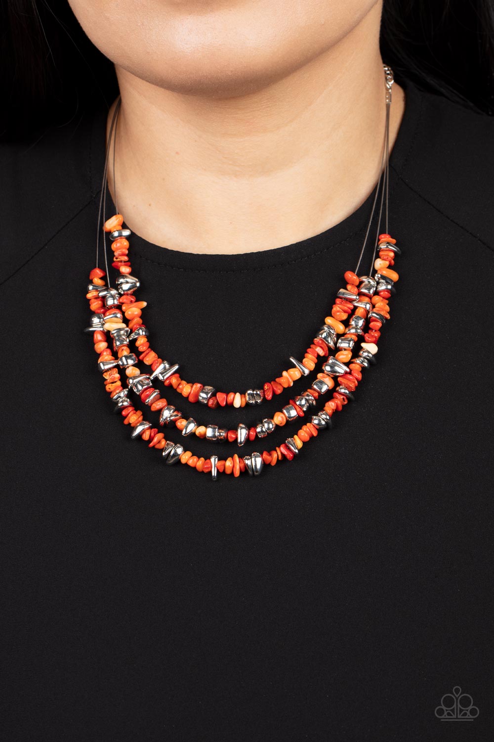An earthy collection of raw cut silver and orange pebbles are threaded along dainty wires below the collar, creating refreshing layers. Features an adjustable clasp closure.  Sold as one individual necklace. Includes one pair of matching earrings.
