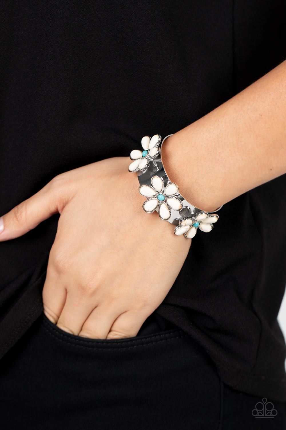 Dotted with turquoise stone centers, a trio of white stone petaled flowers bloom atop a thick silver cuff for a whimsical pop of floral fashion.  Sold as one individual bracelet.