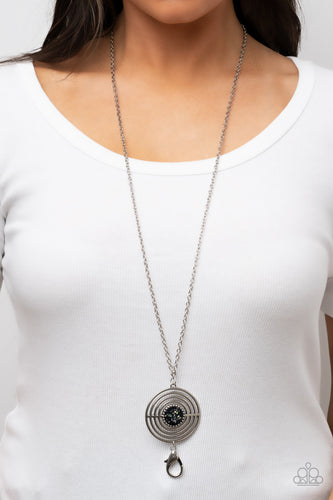Flecked in iridescent shell-like accents, a studded black frame adorns the center of an oversized silver pendant rippling with concentric circles at the bottom of an extended silver chain for a dizzying pop of color. A lobster clasp hangs from the bottom of the design to allow a name badge or other item to be attached. Features an adjustable clasp closure.  Sold as one individual lanyard. Includes one pair of matching earrings.