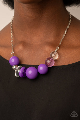 Infused with a single silver bead, an oversized collection of glassy and polished translucent and purple acrylic beads and rings are threaded along an invisible wire below the collar for a flamboyant fashion. Features an adjustable clasp closure.  Sold as one individual necklace. Includes one pair of matching earrings.