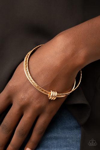 A trio of gold bangles featuring smooth and hammered textures mingles together around the wrist. Three simple gold rings encircle and slide along the bangles, elevating the simple combination into an artistic expression.  Sold as one set of three bracelets.