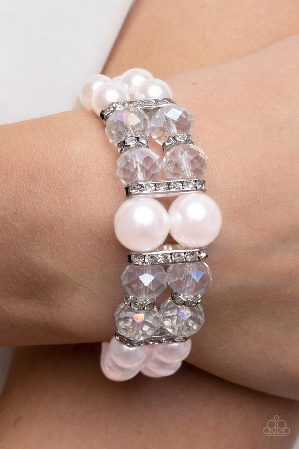 Held together by white rhinestone encrusted silver frames, a stretchy pair of bubbly pink pearl bracelets are infused with white rhinestone encrusted silver rings, iridescent crystal-like beads, and oversized pink pearls for a timeless finish.  Sold as one individual bracelet.