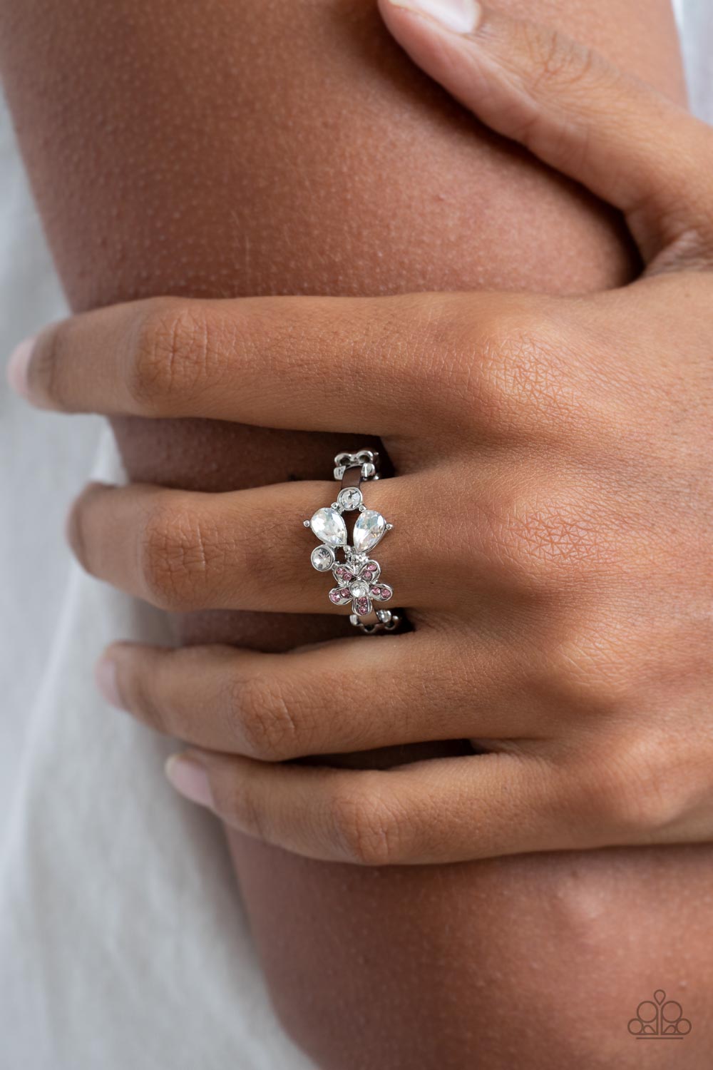 A pink rhinestone dotted floral frame joins round and teardrop white rhinestones atop a dainty silver band, blooming into an enchanting centerpiece across the finger. Features a dainty stretchy band for a flexible fit.  Sold as one individual ring.