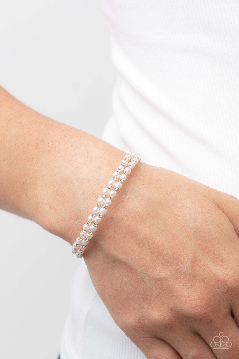 Dainty white pearls and white rhinestone dotted gold fittings alternate along an infinity wire around the wrist, resulting in wraparound shimmer.  Sold as one individual bracelet.