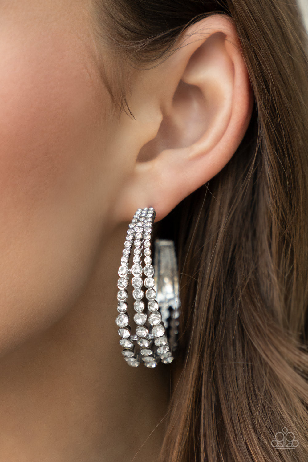 Cascading layers of sparkling white rhinestones plunge into flattened silver plates creating a stunning eye-catching hoop earring. Earring attaches to a standard post fitting. Hoop measures approximately 2