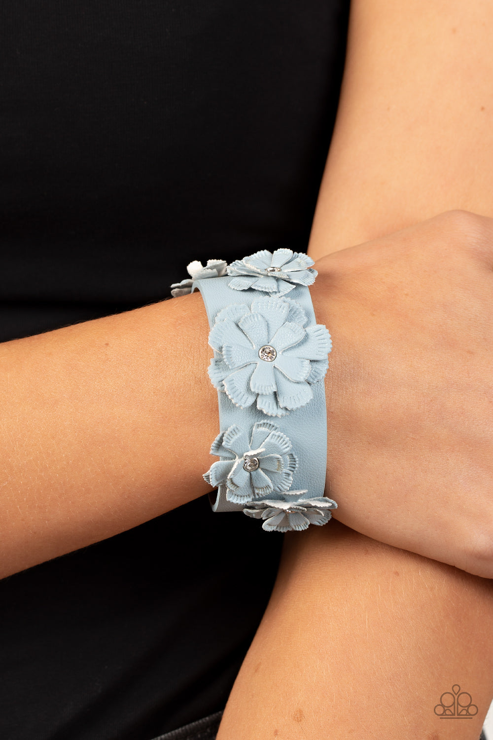 Dotted with dainty white rhinestone centers, textured Glacier Lake leather petals layer into a blooming floral centerpiece atop the front of a thick Glacier Lake leather band for a rustic finish. Features an adjustable snap closure.  Sold as one individual bracelet.