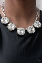 Load image into Gallery viewer, Set in silver pronged fittings, five dramatically oversized brilliant white rhinestones connect across the collar and attach to an oversized silver chain creating a stunning spot-light loving statement piece. Features an adjustable clasp closure.  Sold as one individual necklace. Includes one pair of matching earrings.
