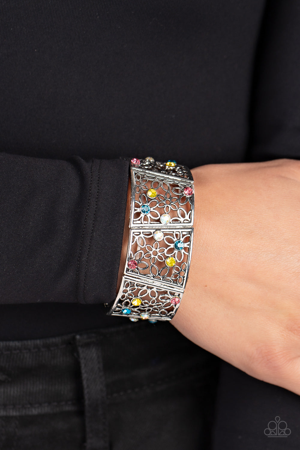 Sporadically dotted with multicolored and iridescent rhinestones, an airy daisy pattern blooms inside trapezoidal silver frames that are threaded along stretchy bands around the wrist for a seasonal statement. Due to its prismatic palette, color may vary.  Sold as one individual bracelet.
