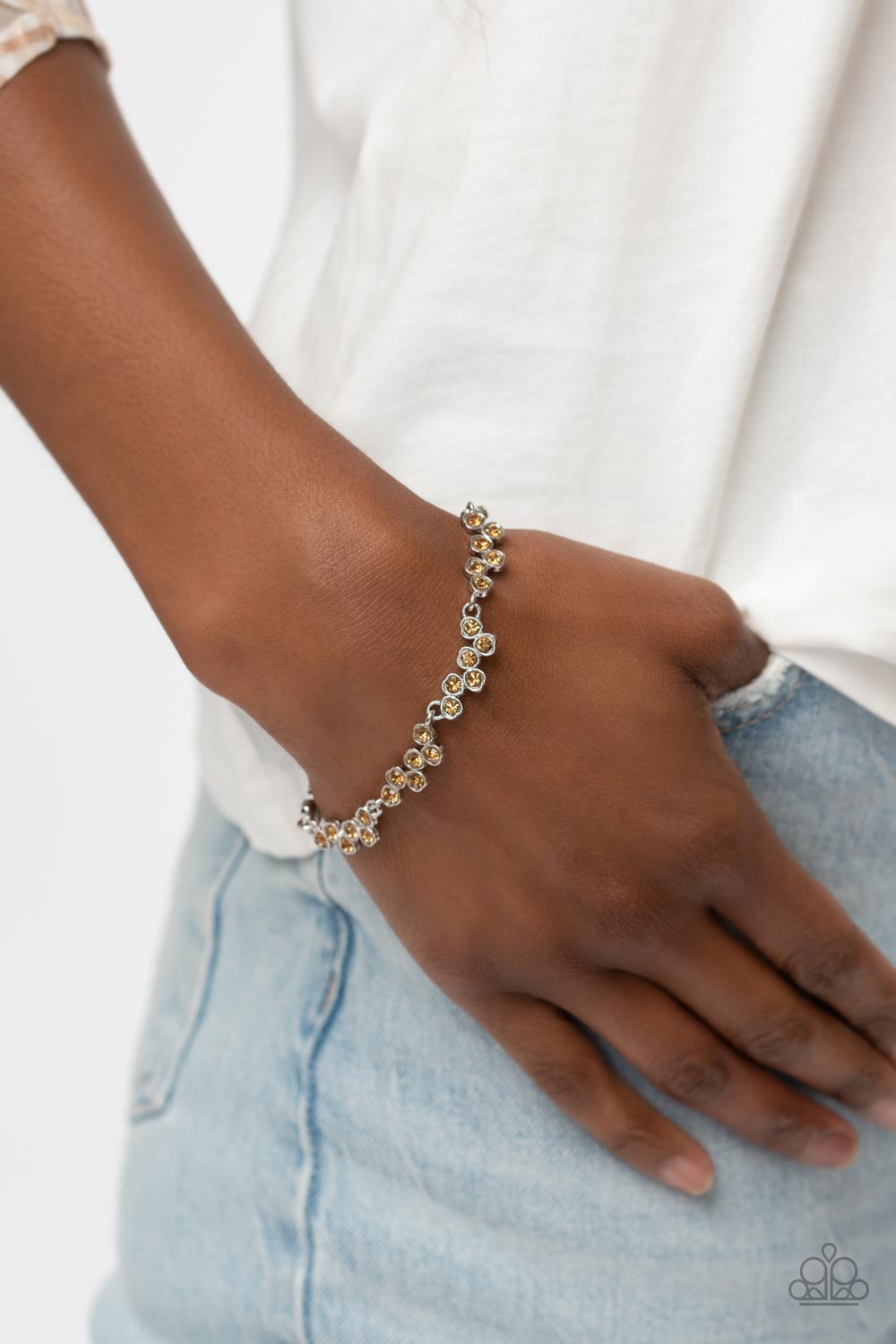 Set in dainty silver heart-shaped frames, staggered clusters of glassy topaz rhinestones delicately link into a flirtatious hint of sparkle around the wrist. Features an adjustable clasp closure.  Sold as one individual bracelet.