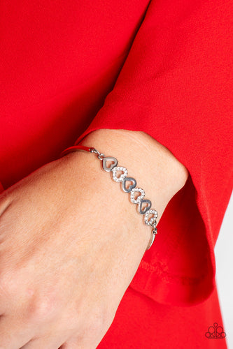 Silver, heart-shaped silhouettes are tilted on their sides, falling in line with variations of the same silver frames encrusted in white rhinestones. The alternating pattern of metallic sheen and glittery shimmer adds eye-catching detail, as the hearts connect into a curved pendant that curls around the wrist. Features an adjustable clasp closure.  Sold as one individual bracelet.