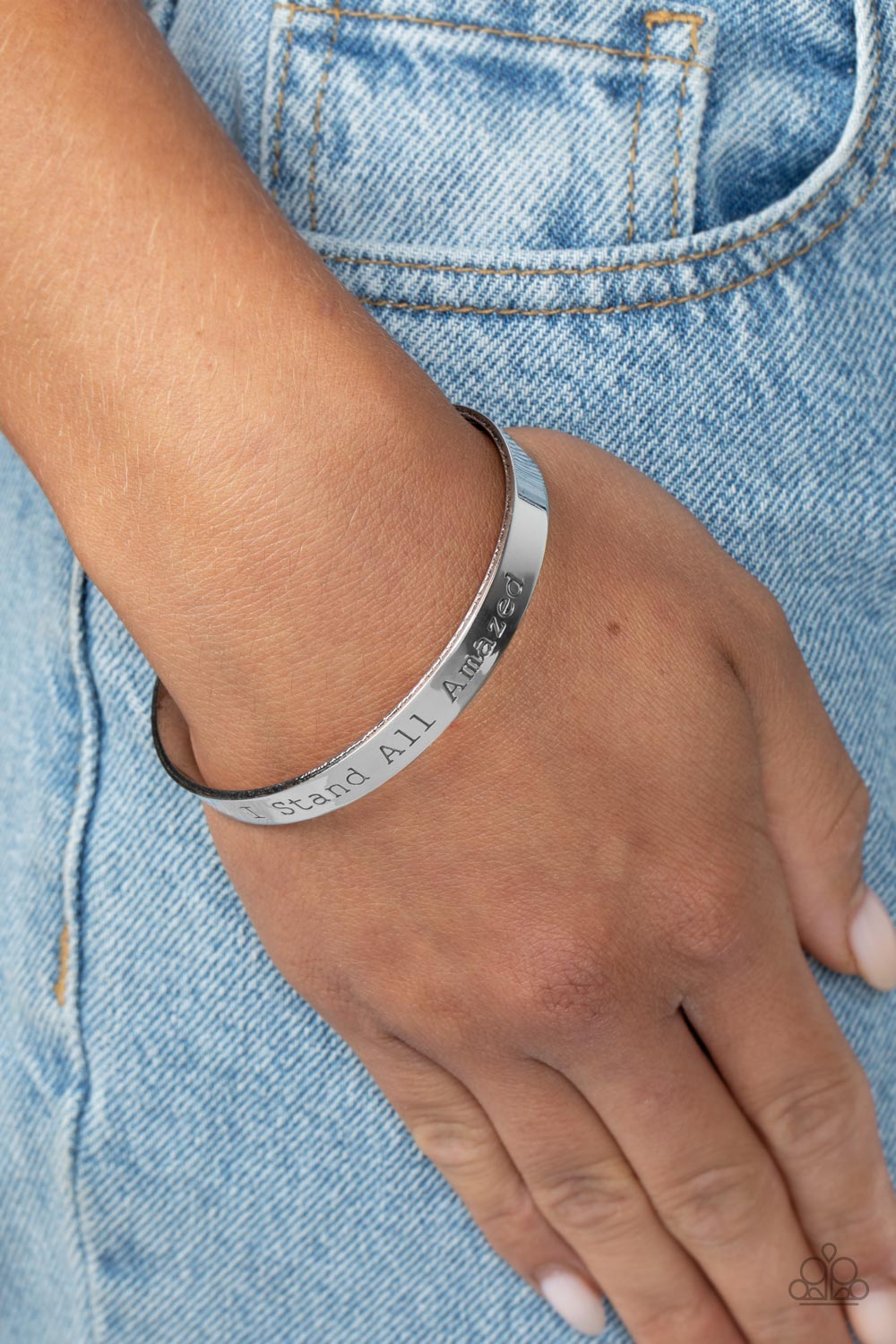 A simplistic, shiny, silver cuff is stamped with the phrase 