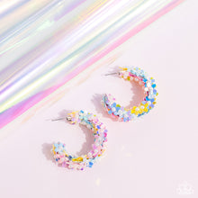 Load image into Gallery viewer, A floral explosion, encompassing the entirety of a thick silver hoop, features reflective light blue, pink, and yellow flowers dotted with dainty pearl centers for a dreamy, whimsicality below the ear. Earring attaches to a standard post fitting. Hoop measures approximately 1 1/2&quot; in diameter.  Sold as one pair of hoop earrings.
