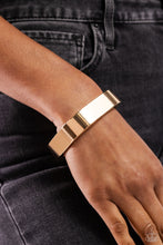 Load image into Gallery viewer, Featuring a sleek, high-sheen finish, a thick gold cuff asymmetrically wraps around the wrist, creating a tilted square centerpiece for a monochromatic staple. Features a hinged closure.  Sold as one individual bracelet.
